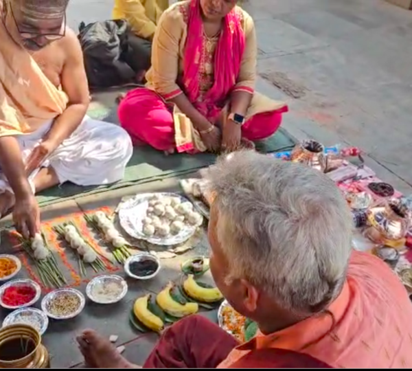 Priest performing Asthi Visarjan rituals with pooja samagri near river ganga.