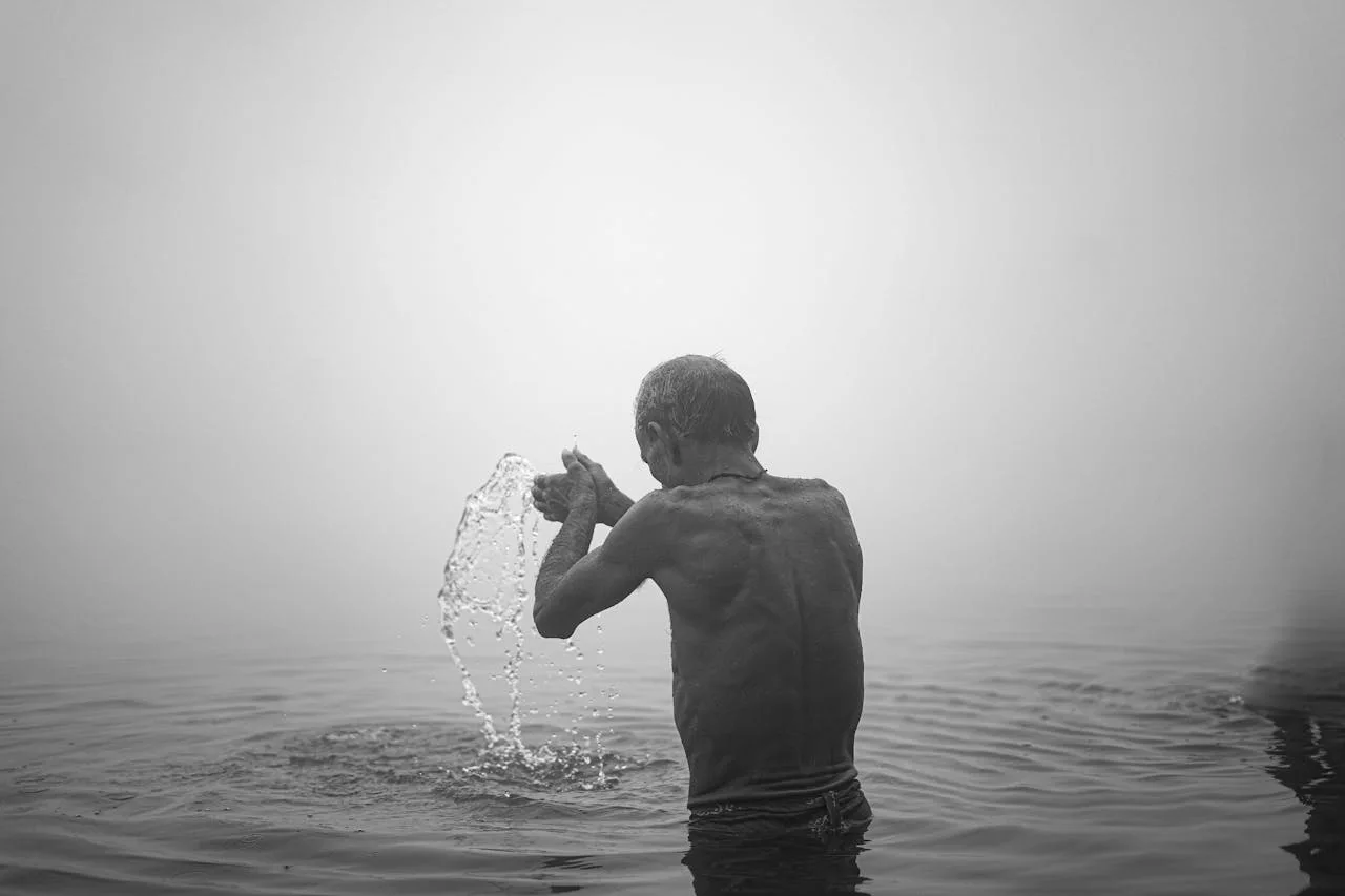 Devotee standing in the holy Ganga river at Varanasi with folded hands offering prayers.