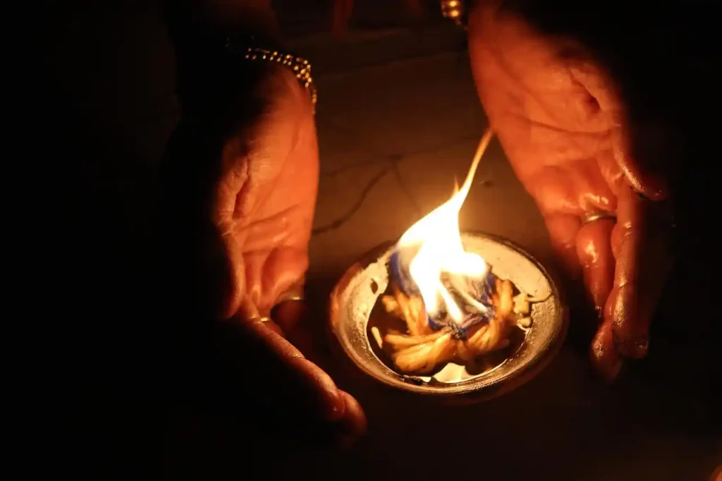 Close-up of a pair of hands gently cupping a lit clay diya