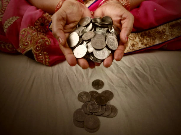 Hands holding coins symbolizing Pind Daan cost and donation during rituals in Varanasi