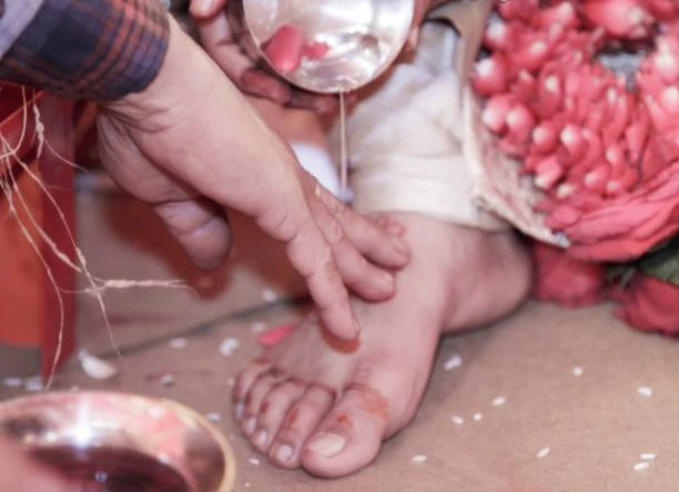 Devotee performing ritual foot washing and offering during initial step of Pind Daan ceremony in Varanasi