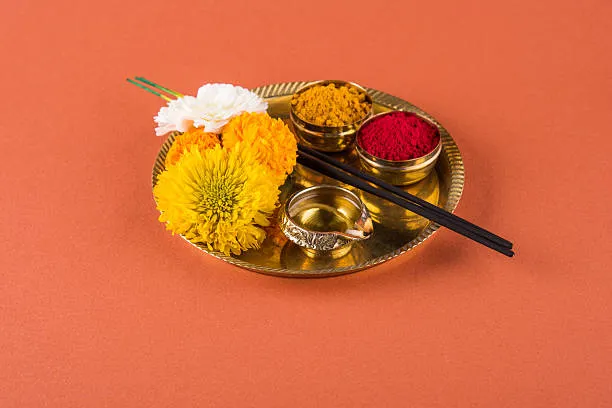 Traditional Puja thali with diya, rice, flowers, and fruits used in rituals for Pitru Dosh