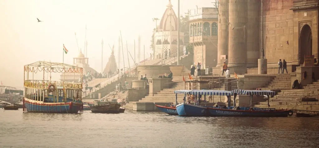Boats on the Ganga river with Varanasi ghats in the background, perfect for booking motor boat rides.