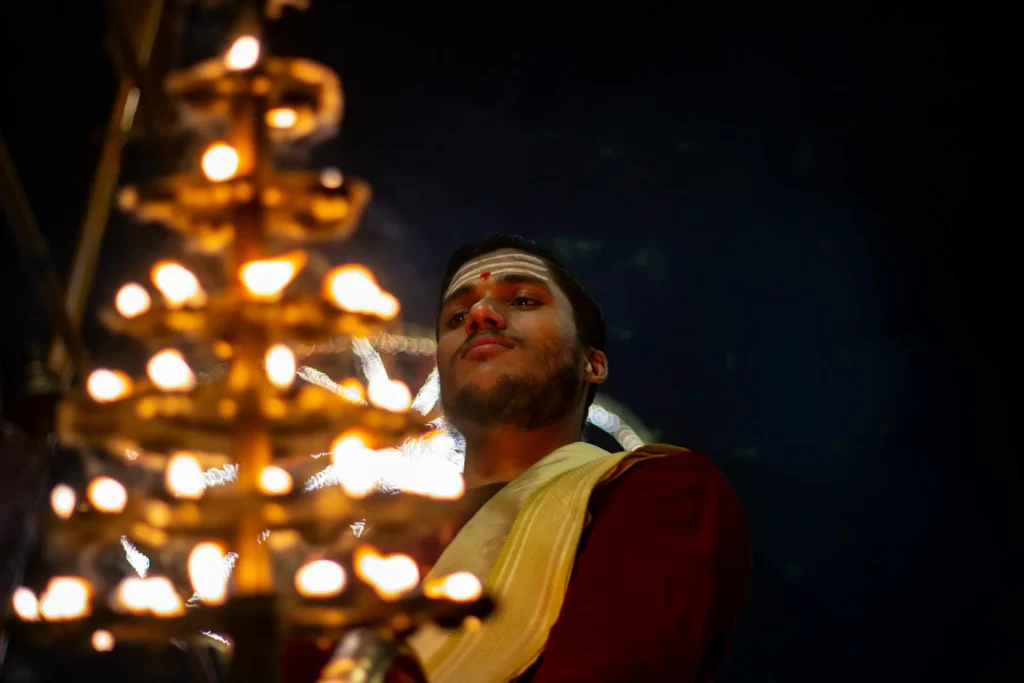 Priest performing Ganga Aarti during evening bajra boat ride at Dashashwamedh Ghat in Varanasi.